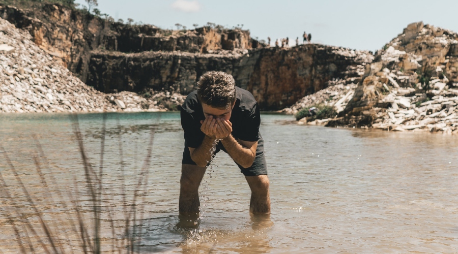 Muž si umýva tvár v rieke
