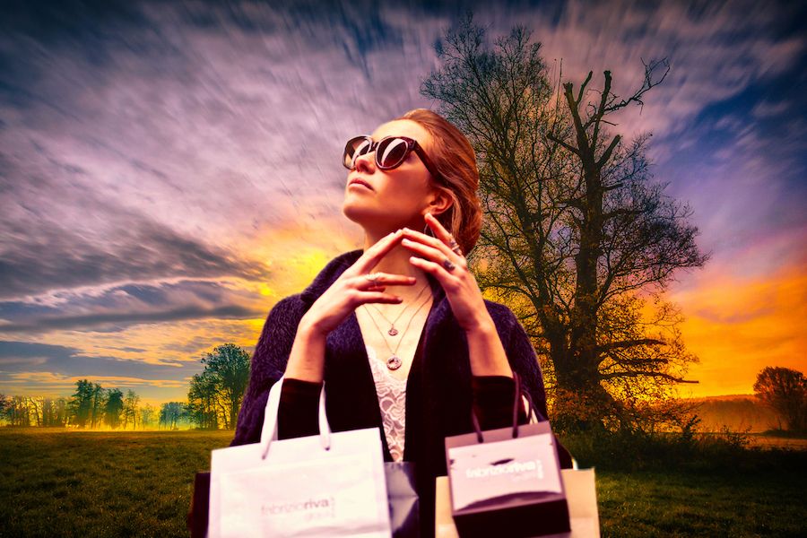Žena s nákupnými taškami v prírode so slnečnými okuliarmi