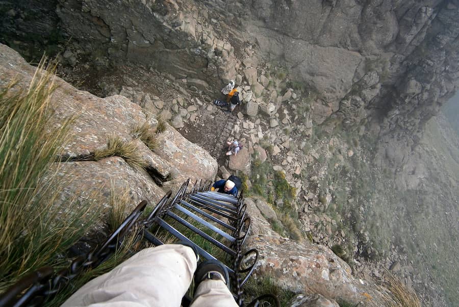 Ľudia lezúci v horách po rebríku