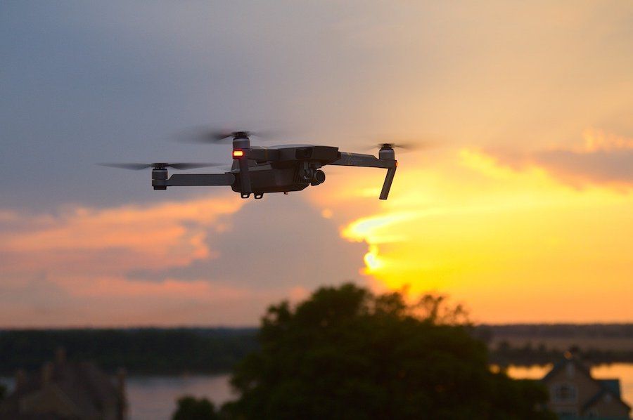 Lietajúci dron na oblohe pri západe Slnka